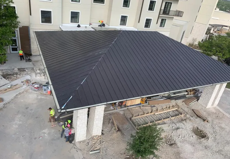 Metal roofing installation team working on a commercial building in Lee